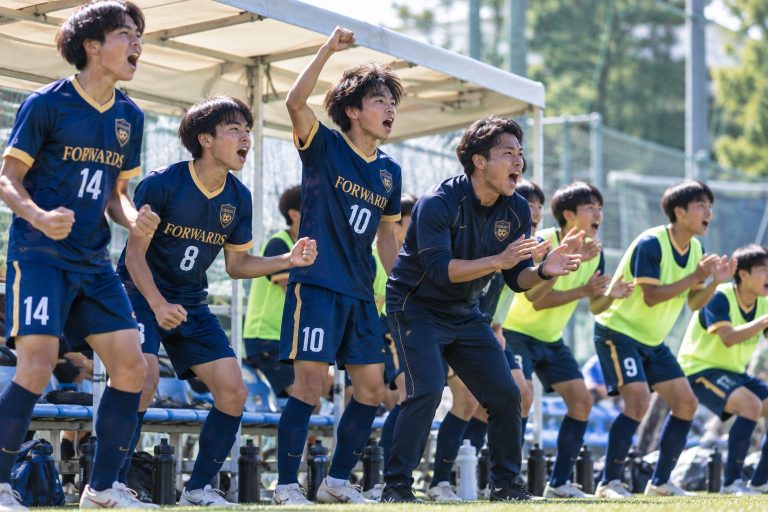 ベンチから声援を送る選手とコーチ